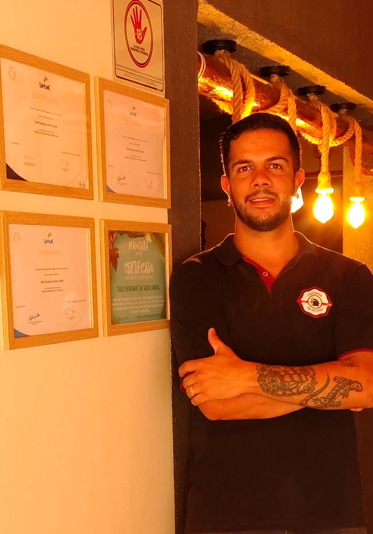 Julio Cabral ao lado de certificados emoldurados; a área com dados pessoais foi removida da imagem publicada.
