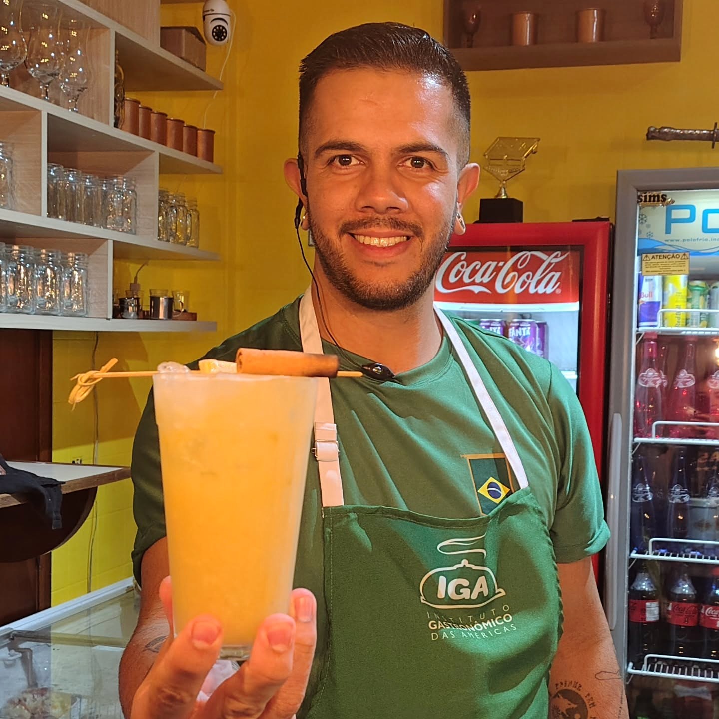 Julio Cabral apresentando uma bebida clara em um ambiente de bar.